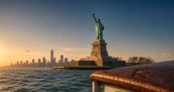 The Statue of Liberty at golden hour, the lower-Manhattan skyline behind it across the harbour